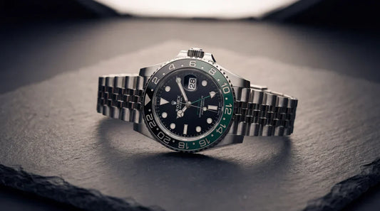 a rolex gmt watch on its side on a black slate board