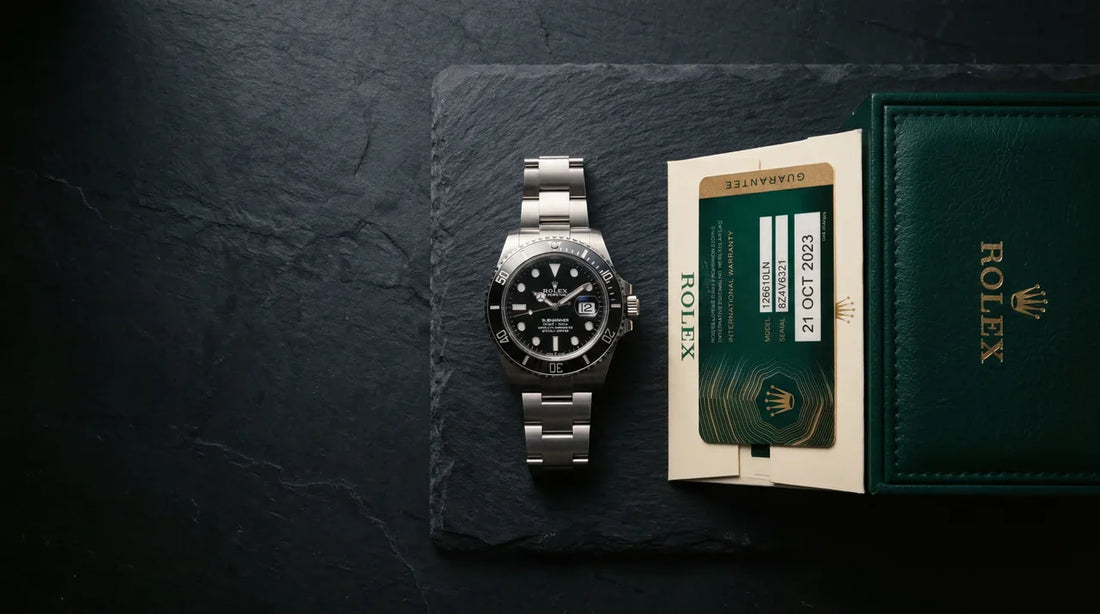 Rolex Submariner ref 126610LN with black dial and oyster bracelet on dark slate, displayed with original Rolex green warranty card and guarantee booklet, showing full box and papers that increase Rolex trade in value
